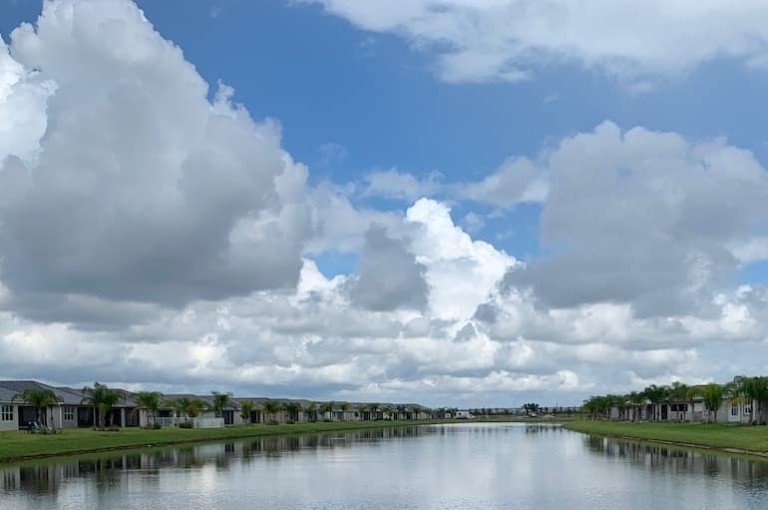 Looking over a housing estate from the water with lots of blue cloudy sky above