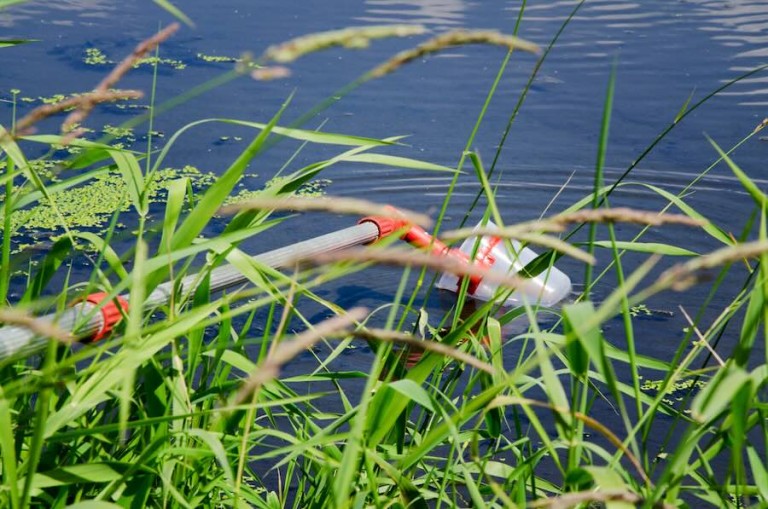 A pole collecting water from a lake to make pH checks