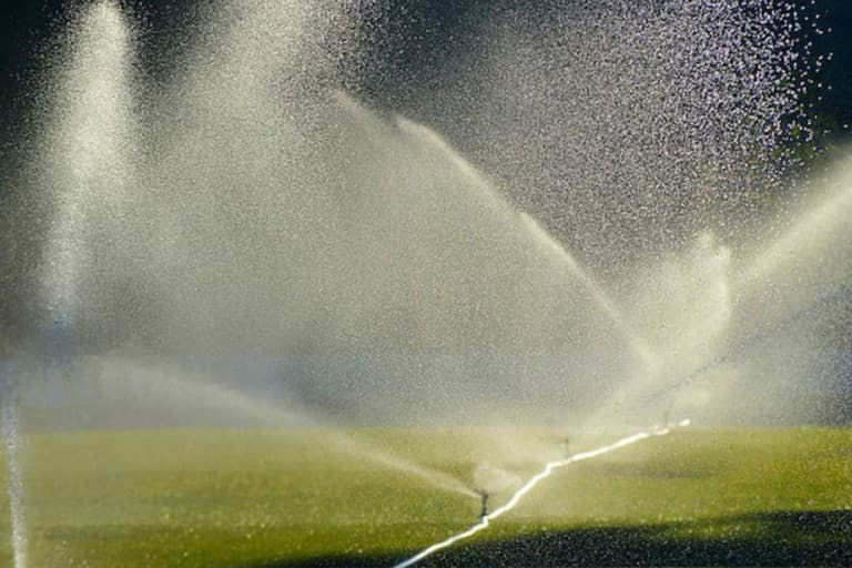 Sprinklers firing water over some grass