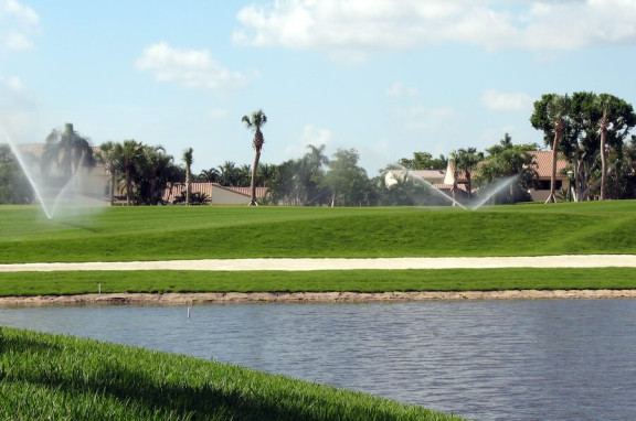 Water spraying from irrigation sprinklers over grass on a housing community estate