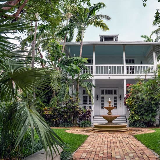 Palm trees and green lawn at the front of a large house in Florida