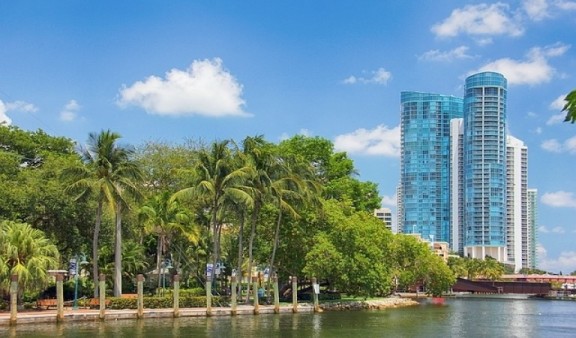 Modern looking office building in the distance with palm trees and river in the forefront