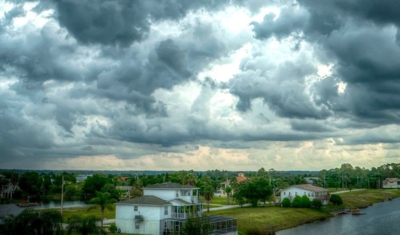 Heavy dark cloud over a town with lots of trees and a river running through