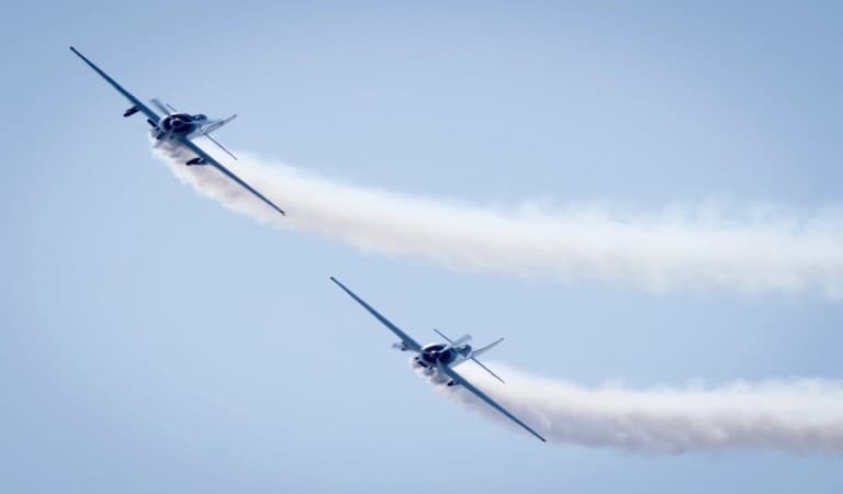 Two planes flying in the sky with vape trails