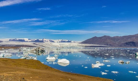 Icebergs in the sea with hills in the distance