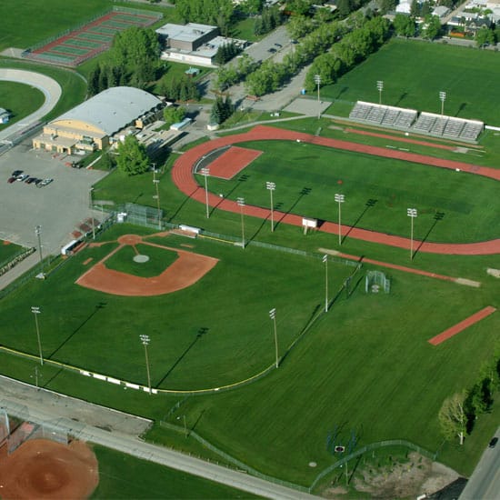 Birds eye view of a athletics track and baseball field with green grass