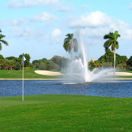 Water shooting up from a fountain next to a golf course